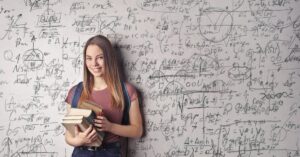 An international student holding books standing in front of a chalkboard deciding what to study in Germany - Internationale Studierende bei der Studienwahl in Deutschland