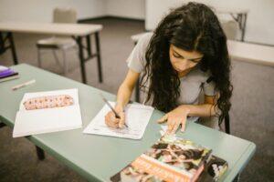 A young woman taking a test in a classroom, concentrating on her exam paper.